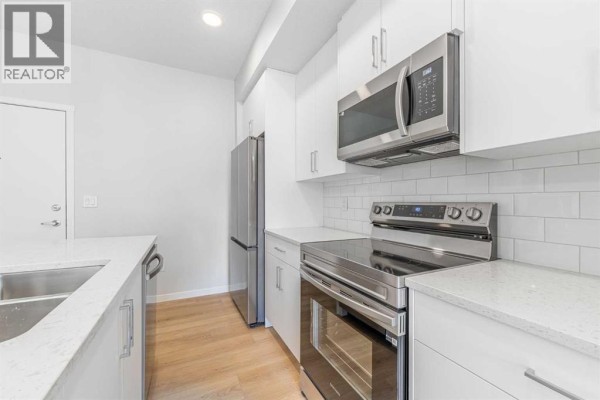 Kitchen with white cabinets, stainless steel refrigerator, oven, and white subway tile backsplash. - 5413, 20295 Seton Way Se, Calgary
