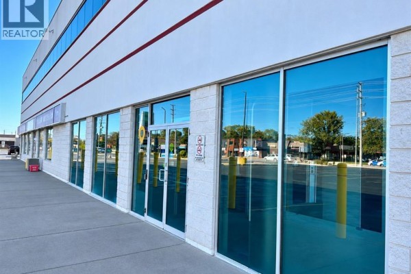 Side view of a commercial building with large glass windows and parking. - 5415 Tecumseh Road East, Windsor