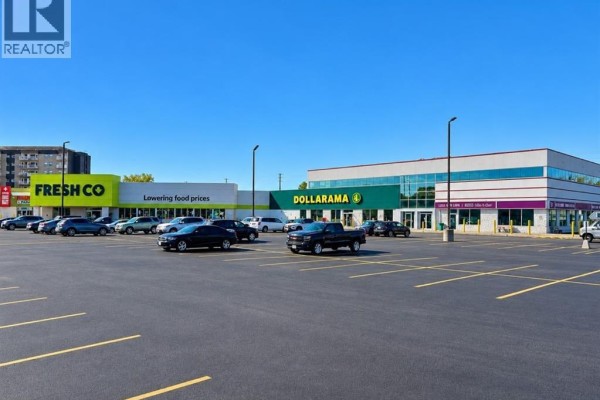 Wide view of a commercial strip mall with multiple businesses and parking lot. - 5415 Tecumseh Road East, Windsor