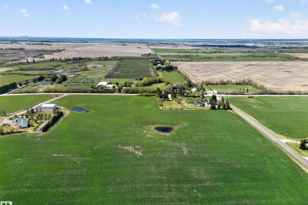 Expansive aerial view of the rural property featuring fields, homes, and outbuildings. - 54175 Rge Road 220, Rural Strathcona County