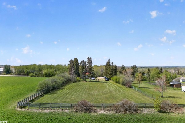 Aerial view of a cleared grassy lot with a wooden fence and trees. - 54175 Rge Road 220, Rural Strathcona County