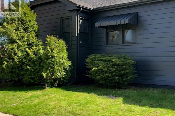 Side view showing dark exterior and shrubs - 5425 Riverside Drive East, Windsor