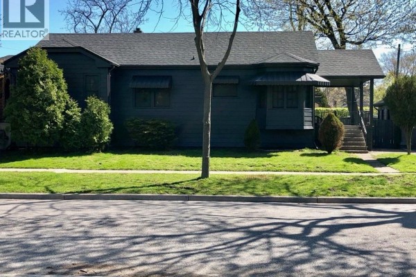 Street view of the house with green lawn and shrubs - 5425 Riverside Drive East, Windsor