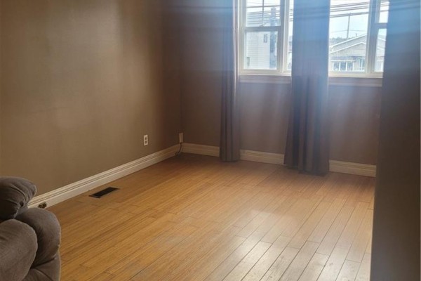 Interior room with light wood floors, brown walls, two windows with brown curtains, and a sofa corner. - 543 Champlain Street, Dieppe