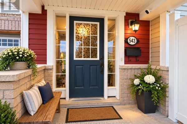 Front door entrance of a red townhouse with a glass-paneled door and seating. - 543 Ensatina Crescent, Ottawa