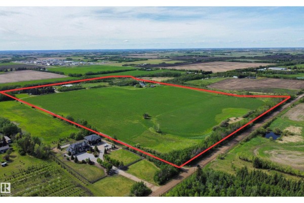 Aerial view of a large, rectangular field outlined in red, showing a large house and landscaping on the lower left. - 54318 Rge Rd 255, St  Albert