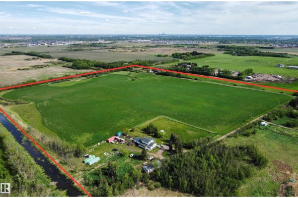 Aerial view of a large, rectangular field outlined in red, with scattered buildings and trees on the property. - 54318 Rge Rd 255, St  Albert