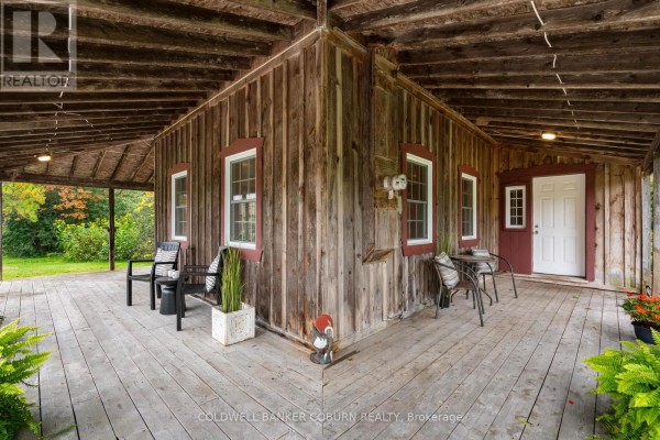 View of the corner porch with seating, wooden walls, white doors, and windows. - 544 Craig Road, North Grenville