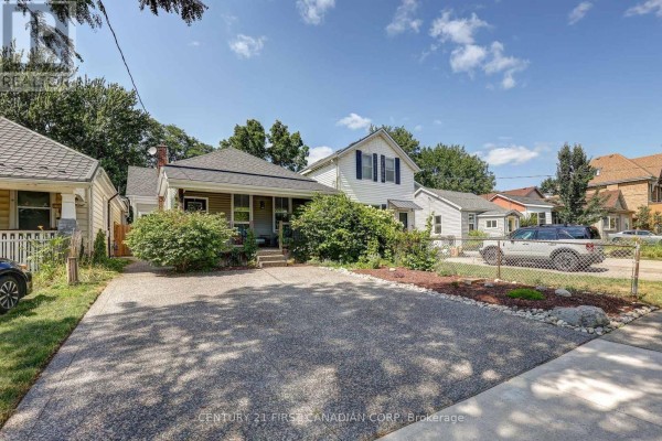 Wide exterior shot of a house with a driveway, featuring mature trees and neighboring properties. - 544 Pall Mall Street, London East