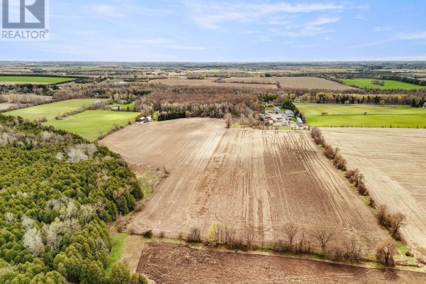 View from the covered front porch of a home, showing two wicker chairs and a rural landscape. - 5445 5th Line, Guelph/eramosa