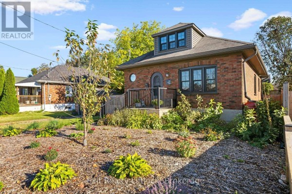 Side view of the brick house showing the front porch and landscaped garden. - 545 Braidwood Avenue, Peterborough