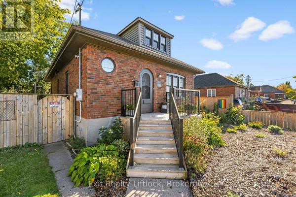 Front steps leading up to the entrance of the brick house with a wooden fence. - 545 Braidwood Avenue, Peterborough
