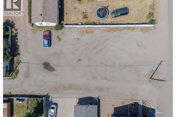 Top-down view of a gravel lot with a parked car, trampoline, and a fence. - 545 Church Avenue, Oliver