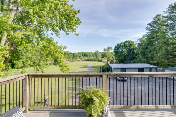 Side view of a tan house with a three-car garage and mature trees. - 545228 Pattullo Avenue, Norwich