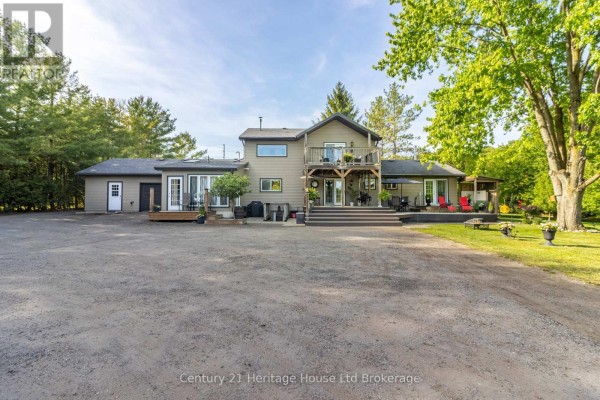 View from a wooden deck overlooking a green field, trees, and farm equipment. - 545228 Pattullo Avenue, Norwich