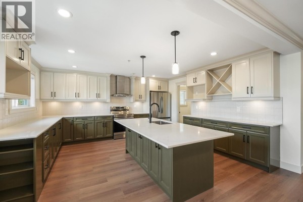 A spacious kitchen featuring green and cream cabinets, a large island, and stainless steel appliances. - 5454 Slocan Street, Vancouver