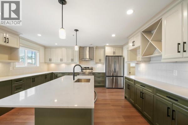 Another view of the kitchen showcasing the island, pendant lights, and ample counter space. - 5454 Slocan Street, Vancouver