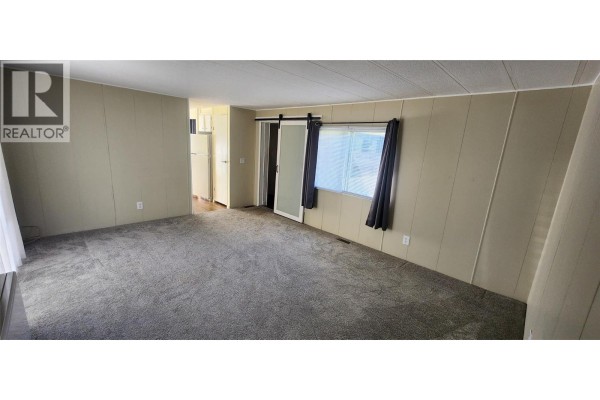 Living room with gray carpet, beige walls, and a sliding barn door. - 5455 Almond Gardens Road Unit# A1, Grand Forks