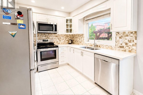 White kitchen with a sink, dishwasher, stove, microwave, and a large window overlooking greenery. - 5456 Palmerston Crescent, Mississauga