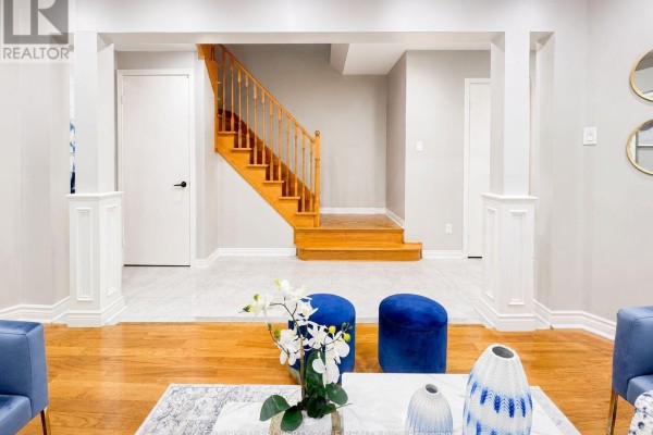 View of a home's interior foyer with a wooden staircase, tiled floors, and living room furniture. - 5456 Palmerston Crescent, Mississauga