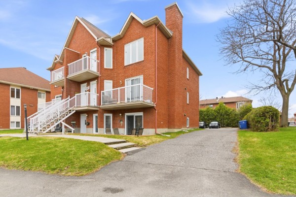 Side exterior view of a brick apartment building with a driveway and trees. - 547 Boul. Des Hautes-plaines, #1, Gatineau
