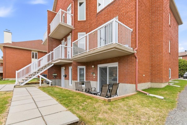 Rear exterior view of an apartment unit with a patio and green lawn. - 547 Boul. Des Hautes-plaines, #1, Gatineau