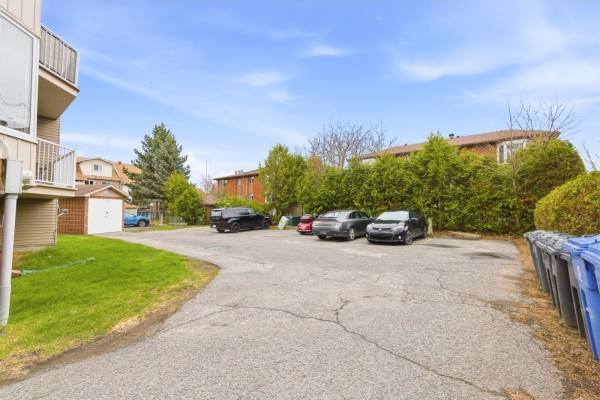 Rear parking lot with multiple cars and green space. - 547 Boul. Des Hautes-plaines, #1, Gatineau