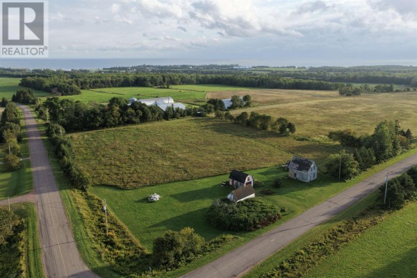 Two white barns with red doors sit on a grassy field with patches of snow. - 547 New Argyle Road, New Argyle