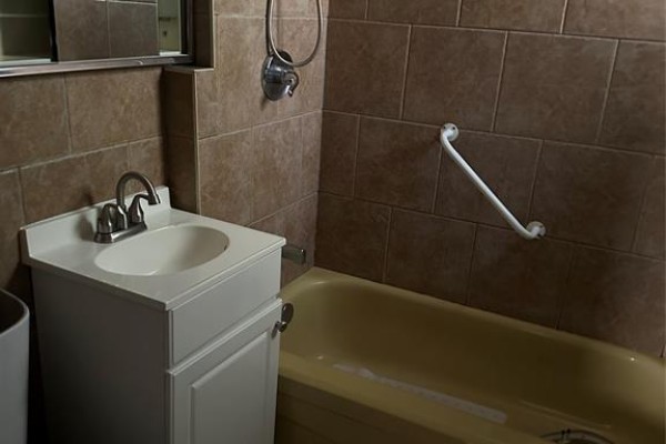 Bathroom with a white vanity, a bathtub, and tiled walls. - 547 Pierre Avenue, Windsor