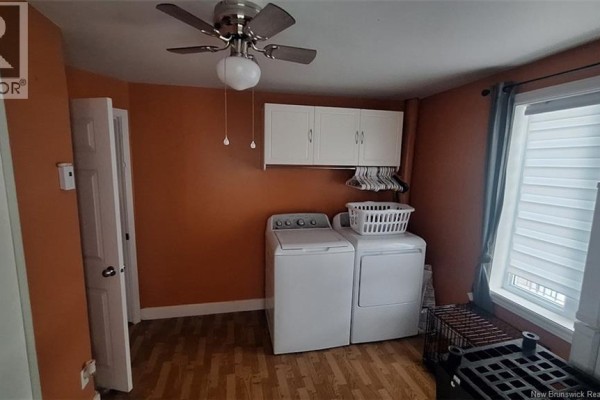 Laundry room with orange walls, white washer and dryer, and overhead white cabinets. - 547 Principale Street, Saint Basile