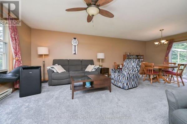 Backyard view of a house with a large wooden deck and sliding glass doors. - 5471 8th Line, Essa