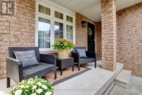 Covered front porch with two wicker chairs, a side table, and potted plants. - 5474 Middleport Crescent, Mississauga
