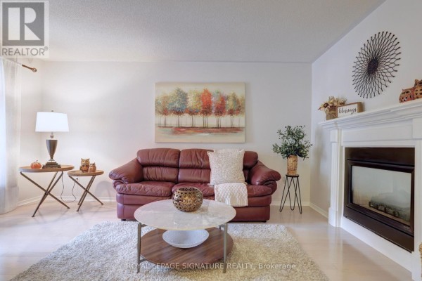 Living room with a red leather sofa, fireplace, coffee table, and light wood flooring. - 5474 Middleport Crescent, Mississauga