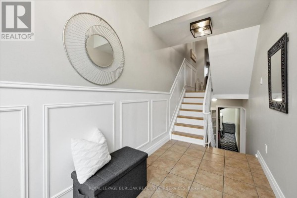 Entranceway with a white front door, beige tiled floor, and a staircase leading up. - 5474 Schueller Crescent, Burlington