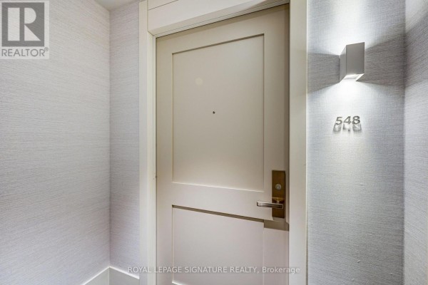Close-up of a closed apartment door labeled 548 with a modern light fixture on the right. - 548 - 26 Gibbs Road, Toronto