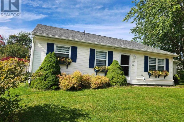 Side exterior view of a white bungalow with manicured green lawn and mature trees. - 549 Robert Clements Drive, Montague