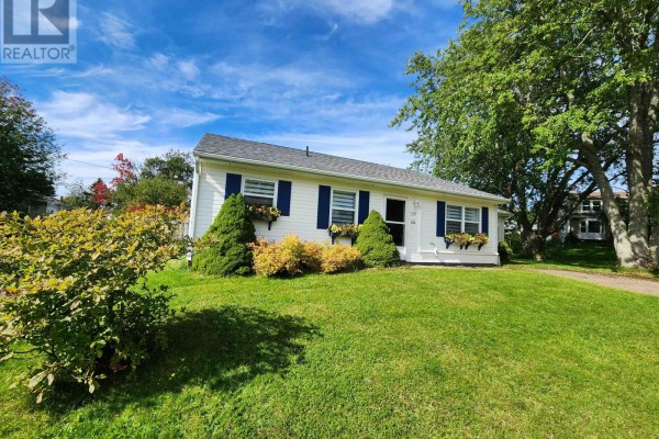 View of the white bungalow from the side yard, showing the roofline and surrounding trees. - 549 Robert Clements Drive, Montague