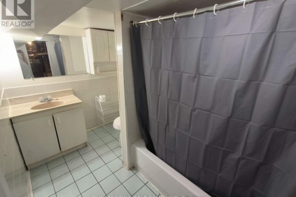 Bathroom with light blue tiled floor, white vanity, and a grey shower curtain. - 55 Chamberlain B1 Avenue, Toronto