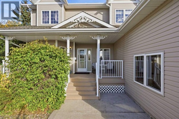 Front entrance with beige siding, white trim, and a covered porch with stairs. - 55 Dietz Close, Red Deer