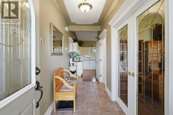 View of the covered front porch with wooden decking, chairs, and a front door. - 55 Dietz Close, Red Deer