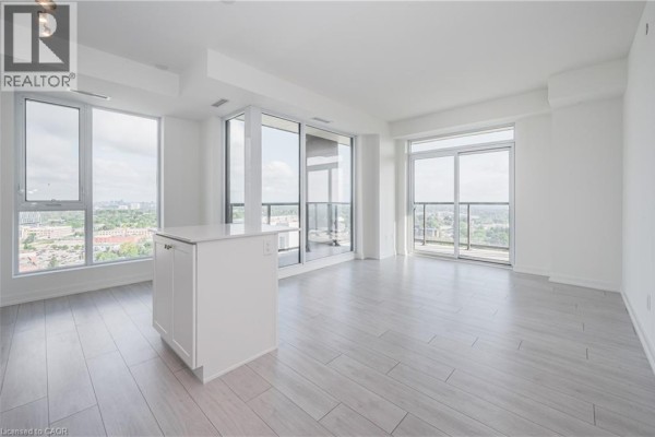 Bright living space with white walls, light wood floors, an island, and large windows overlooking the city. - 55 Duke Street Unit# 2102, Kitchener