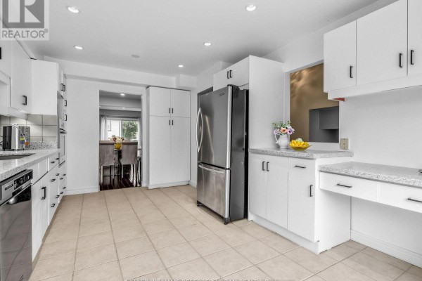 Spacious white kitchen with a large bay window overlooking townhouses across the street. - 55 English Ivyway, Toronto