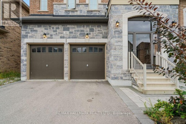 Close-up of the double garage doors and the stone-clad entrance with a concrete driveway. - 55 Marbrook Street, Richmond Hill
