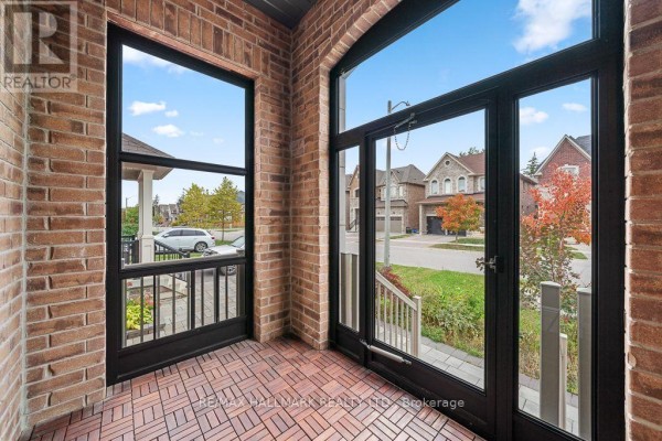 Sunroom interior with brick walls and large glass doors offering a view of the street. - 55 Marbrook Street, Richmond Hill