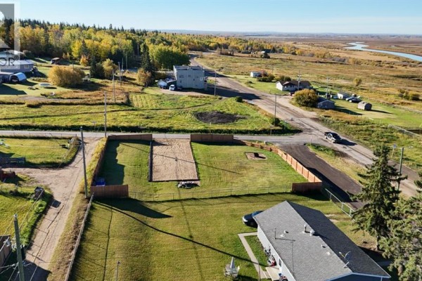 Overhead view of a fenced lot and surrounding neighborhood with trees and fields stretching to the horizon. - #55 Mission Street, Grouard