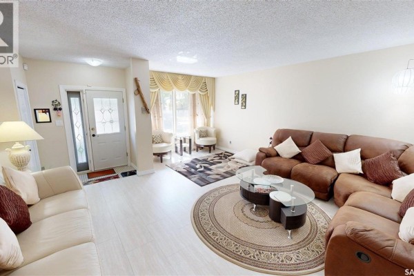 Bedroom with a bed, dresser, closet doors, and beige walls. - 55 Noonan Road, Regina