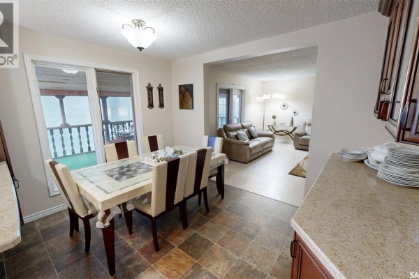 Kitchen with dark wood cabinets, stainless steel appliances, granite countertops, and a window overlooking a snowy landscape. - 55 Noonan Road, Regina
