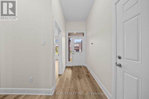 Interior hallway with light beige walls, white trim, and light wood-look laminate flooring leading to the front door. - 55 Robertson Lane, Carleton Place