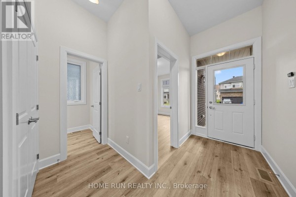 Interior hallway with light beige walls, white trim, and light wood-look laminate flooring leading to the front door and interior rooms. - 55 Robertson Lane, Carleton Place