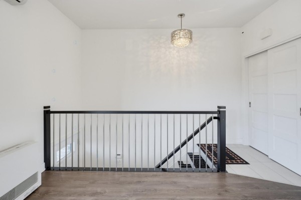 Interior hallway landing with wood floors, white walls, and a modern metal railing. - 55 Rue Du Britannia, #2, Gatineau